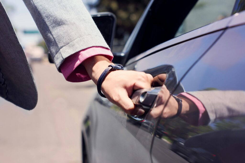 Hand aan de buitenste deurklink van een personenauto