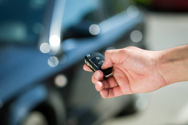 Hand met een autosleutel en afstandsbediening voor een donker autoportier